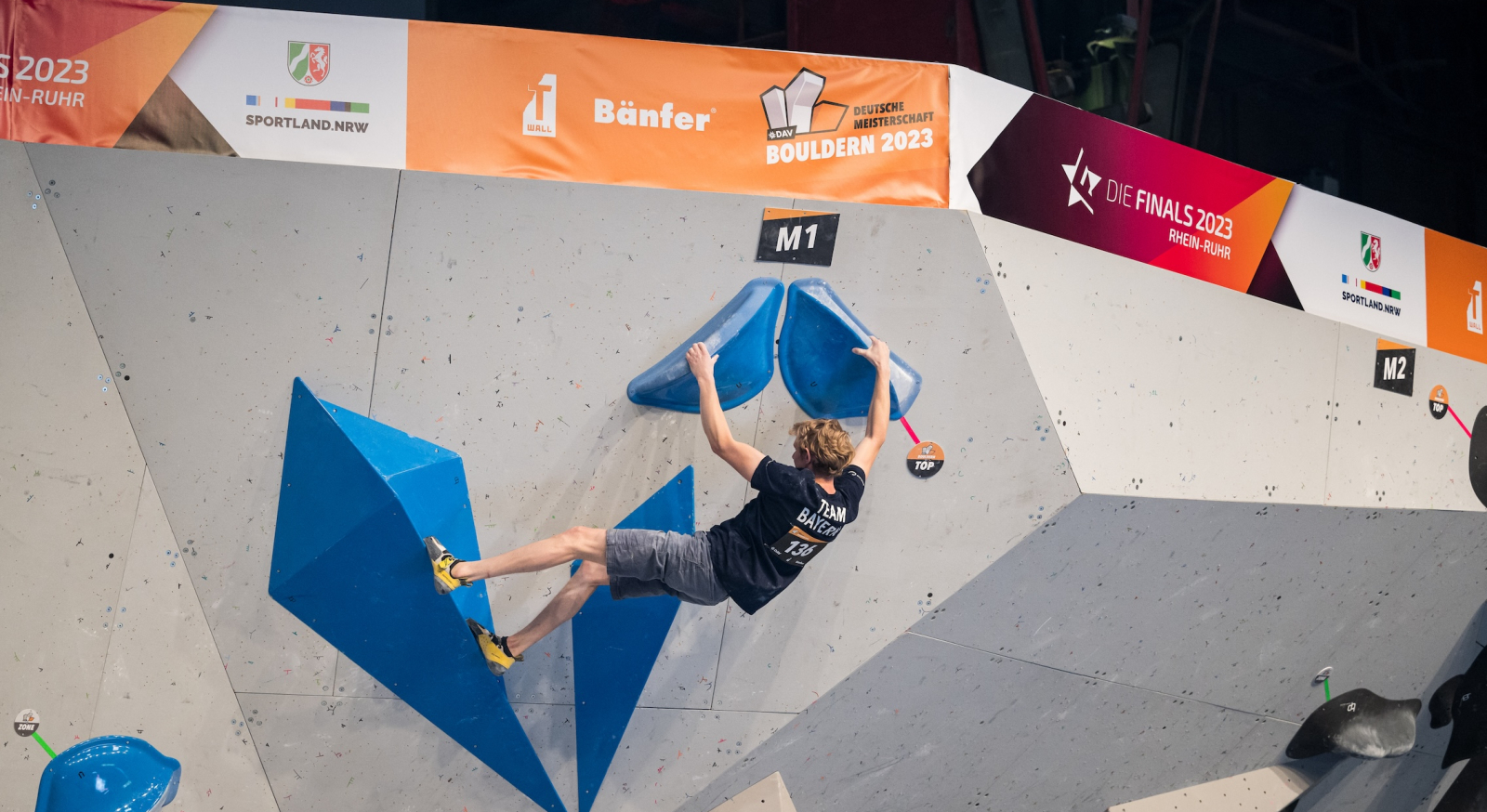 Athlet in schwarzem Shirt an einer Kletterwand bei den Finals